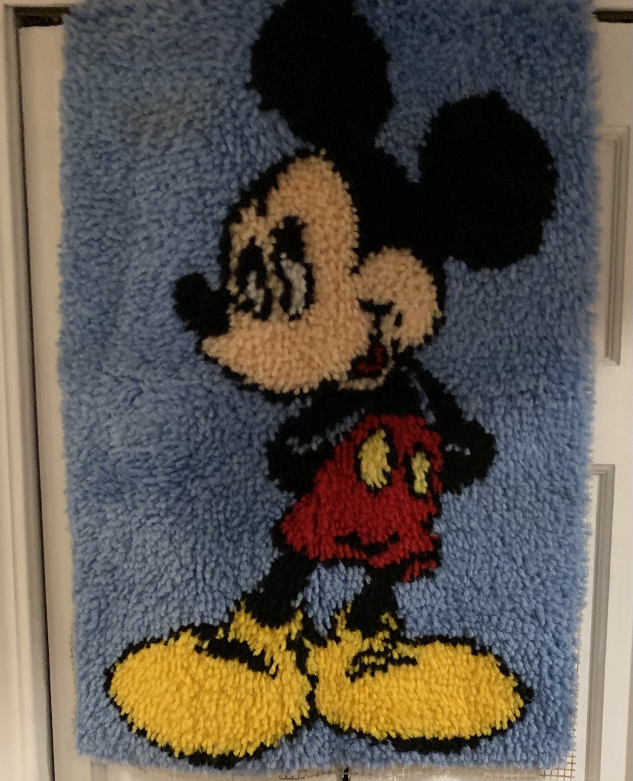 Mickey Mouse latch-hook wall hanging with a blue background, red shorts and yellow shoes